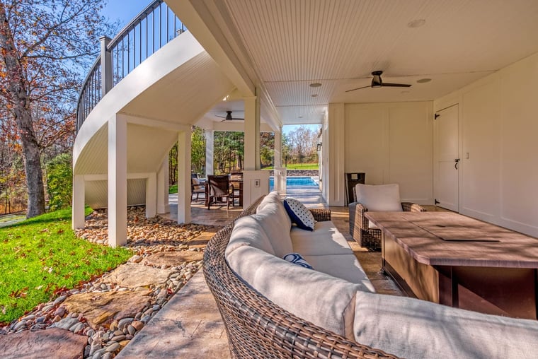 Under deck patio area with furniture and curved staircase to deck