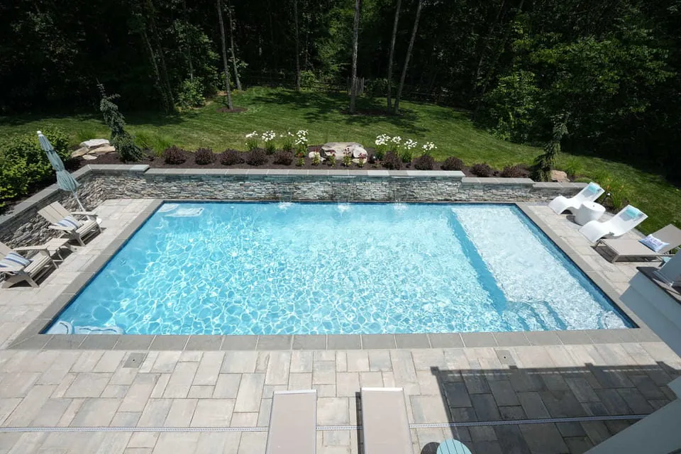 Rectangular gunite pool with paver patio by Deckscapes of VA