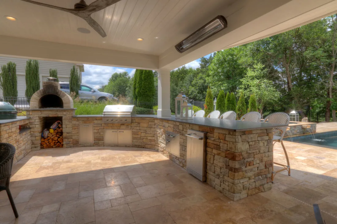 Under deck patio area with outdoor kitchen below Bromic heaters by Deckscapes of VA
