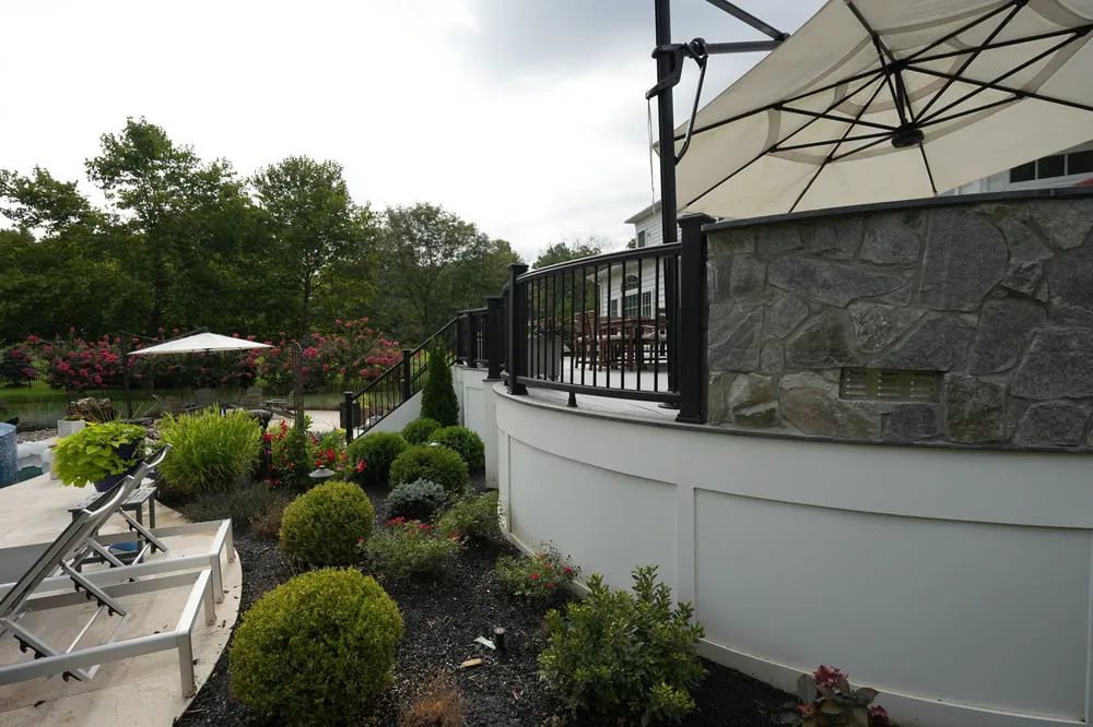 Plants and landscaping around curved deck by Deckscapes of VA