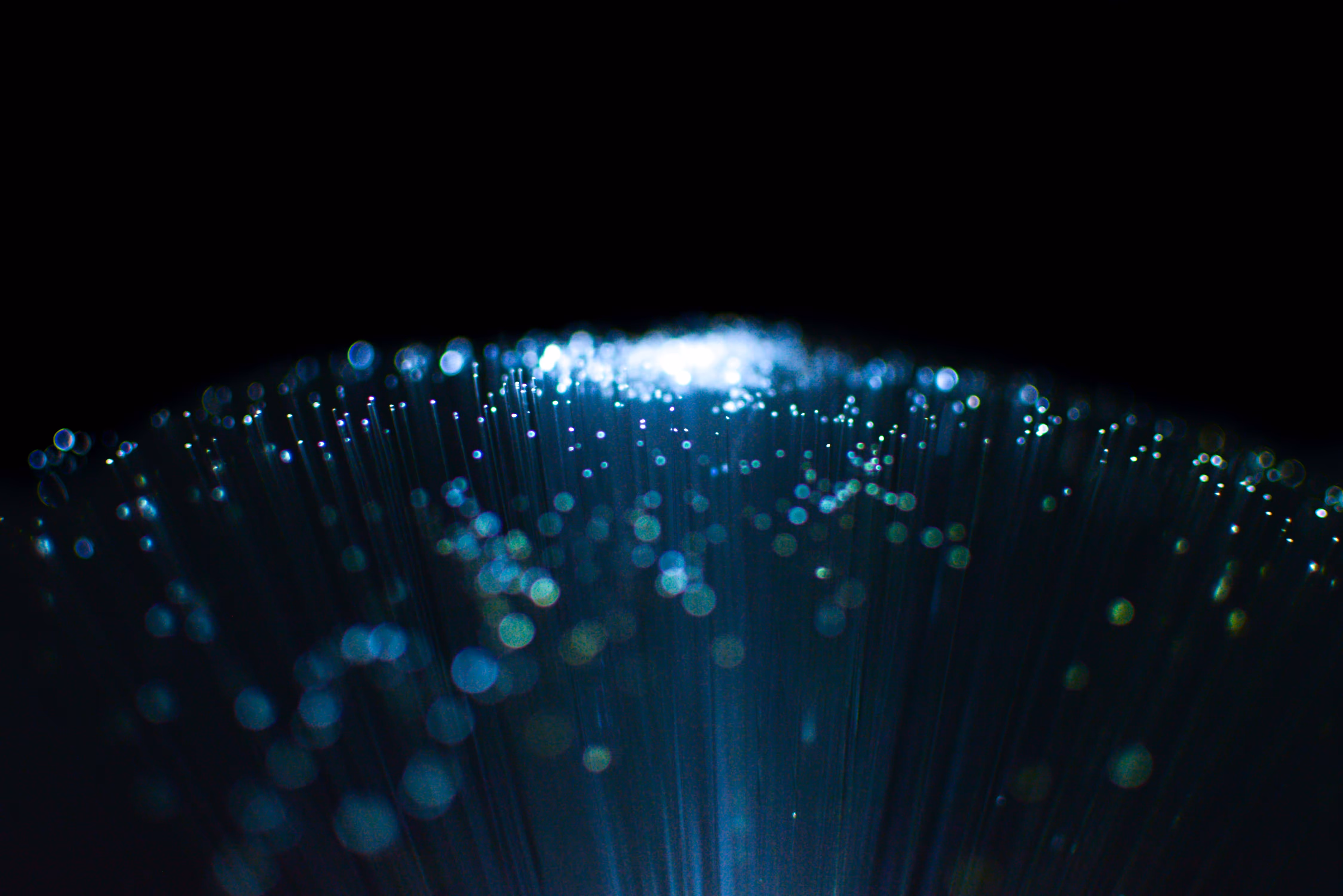 Abstract flowing lines with blue and white glowing dots on a dark background, resembling data streams or fiber optic cables.