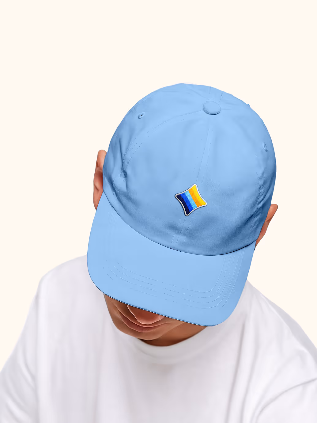 Person wearing a light blue baseball cap with a small multicolored striped patch on the front.