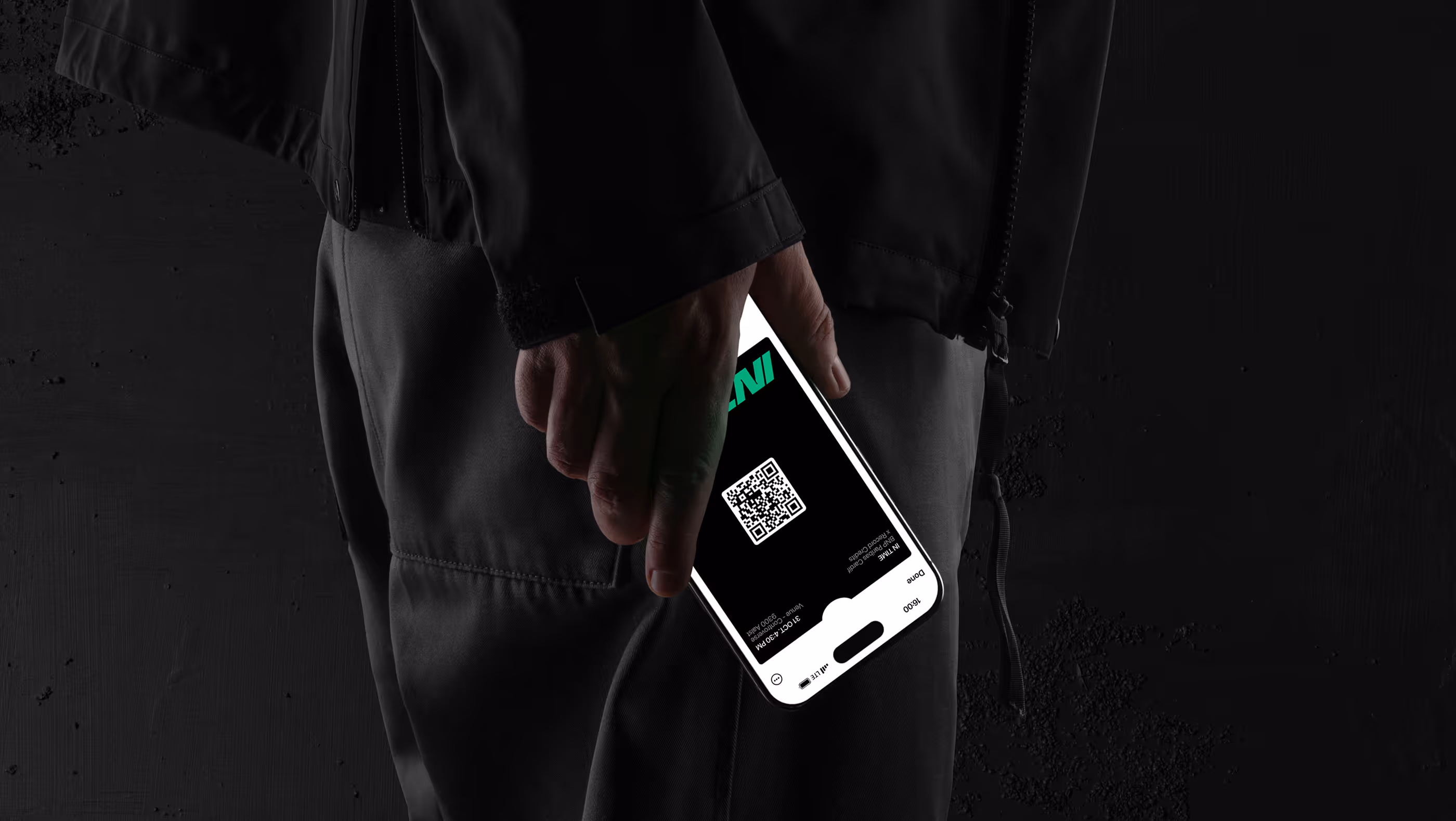 Person holding a smartphone displaying a QR code on the screen against a dark background.