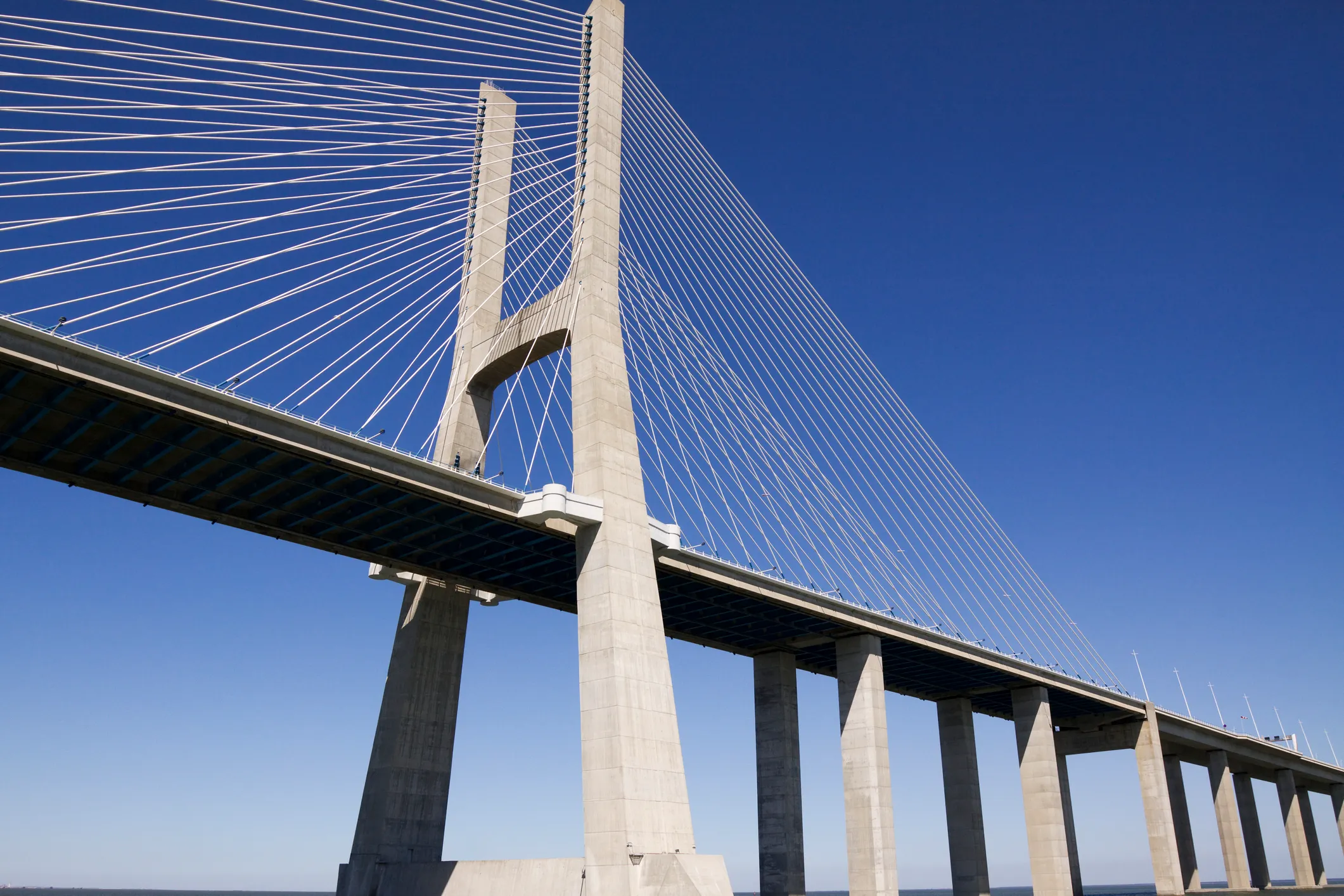 Modern cable-stayed bridge with tall concrete pillars against a clear blue sky.