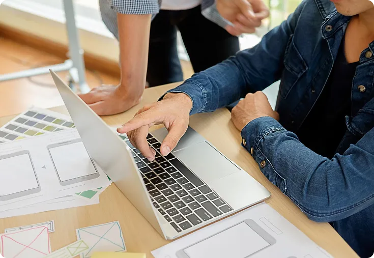 Équipe de développeurs devant un pc et discutant à propos de la création d'un site internet