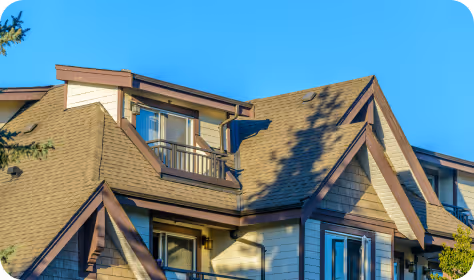 Close-up of a modern house roof with dormer windows under a clear blue sky.