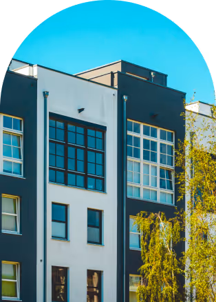 Modern residential building facade with large windows and contrasting white and dark gray walls under a clear blue sky.