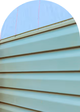 Close-up of light green exterior vinyl siding on a building wall with a light blue background.