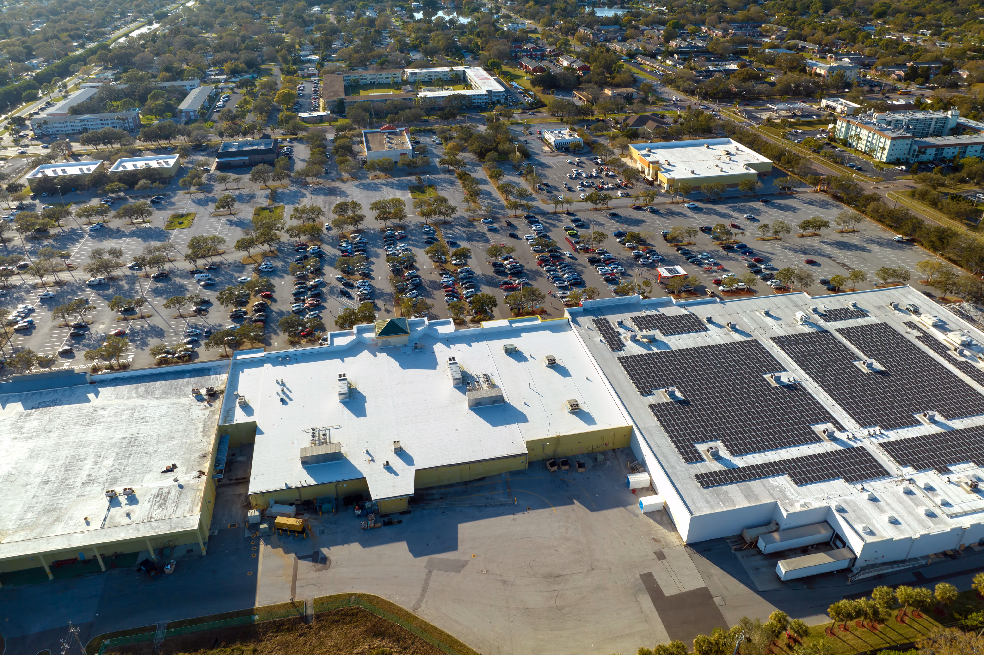 Aerial view of a commercial building roof and surrounding properties