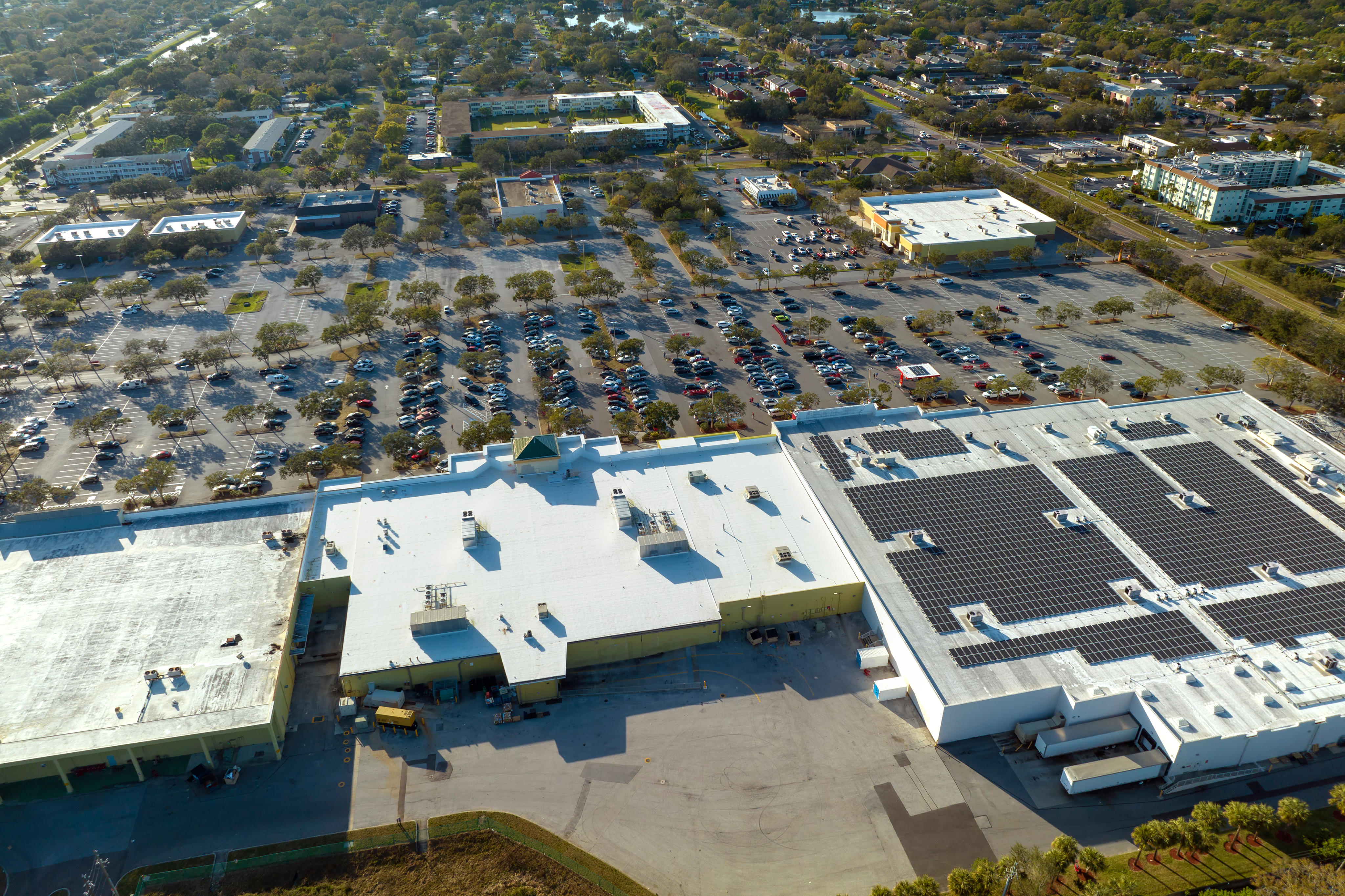 Aerial view of a commercial building roof and surrounding properties