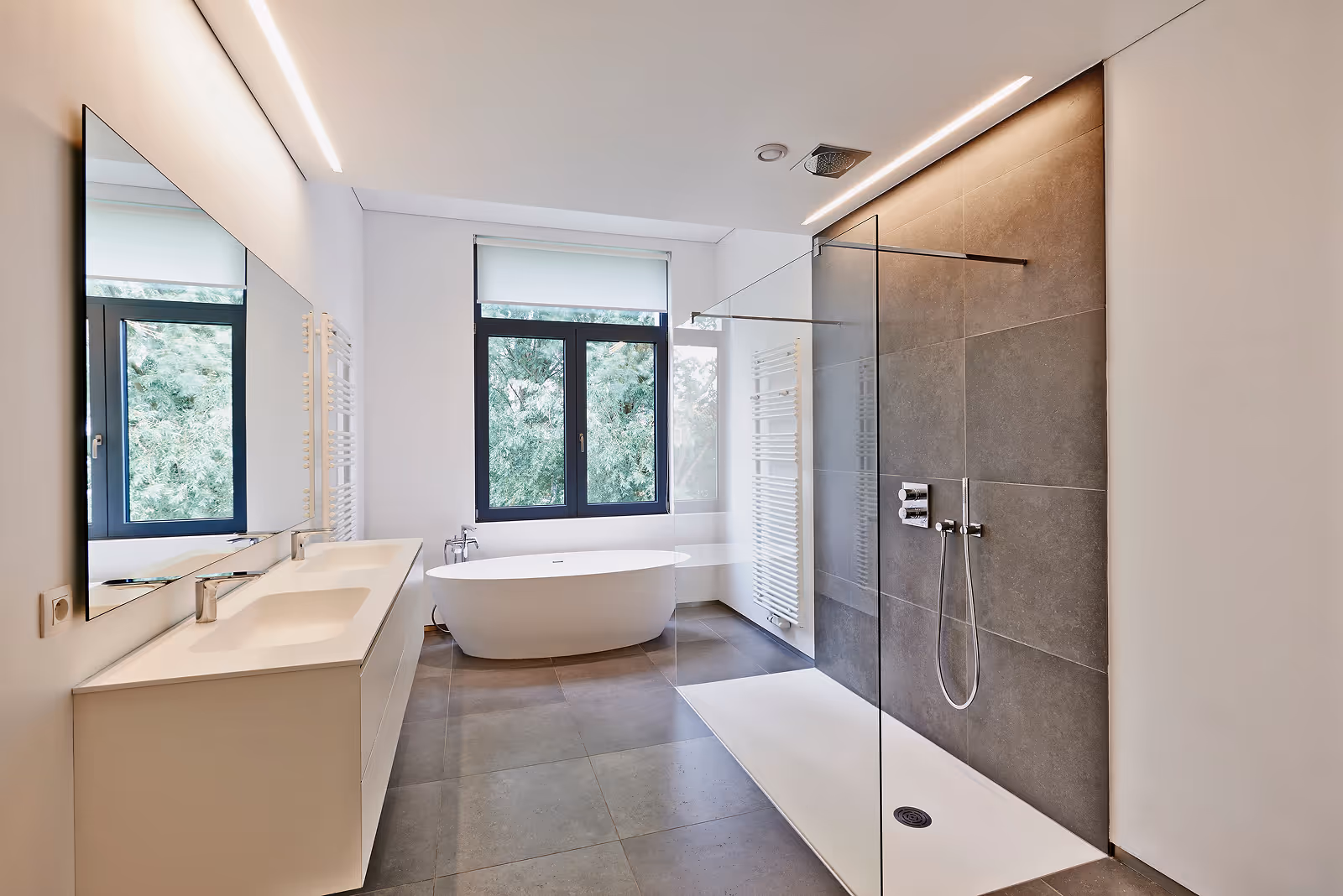 Modernes Badezimmer mit freistehender Badewanne, Doppelwaschbecken und begehbarer Dusche mit Glaswand.