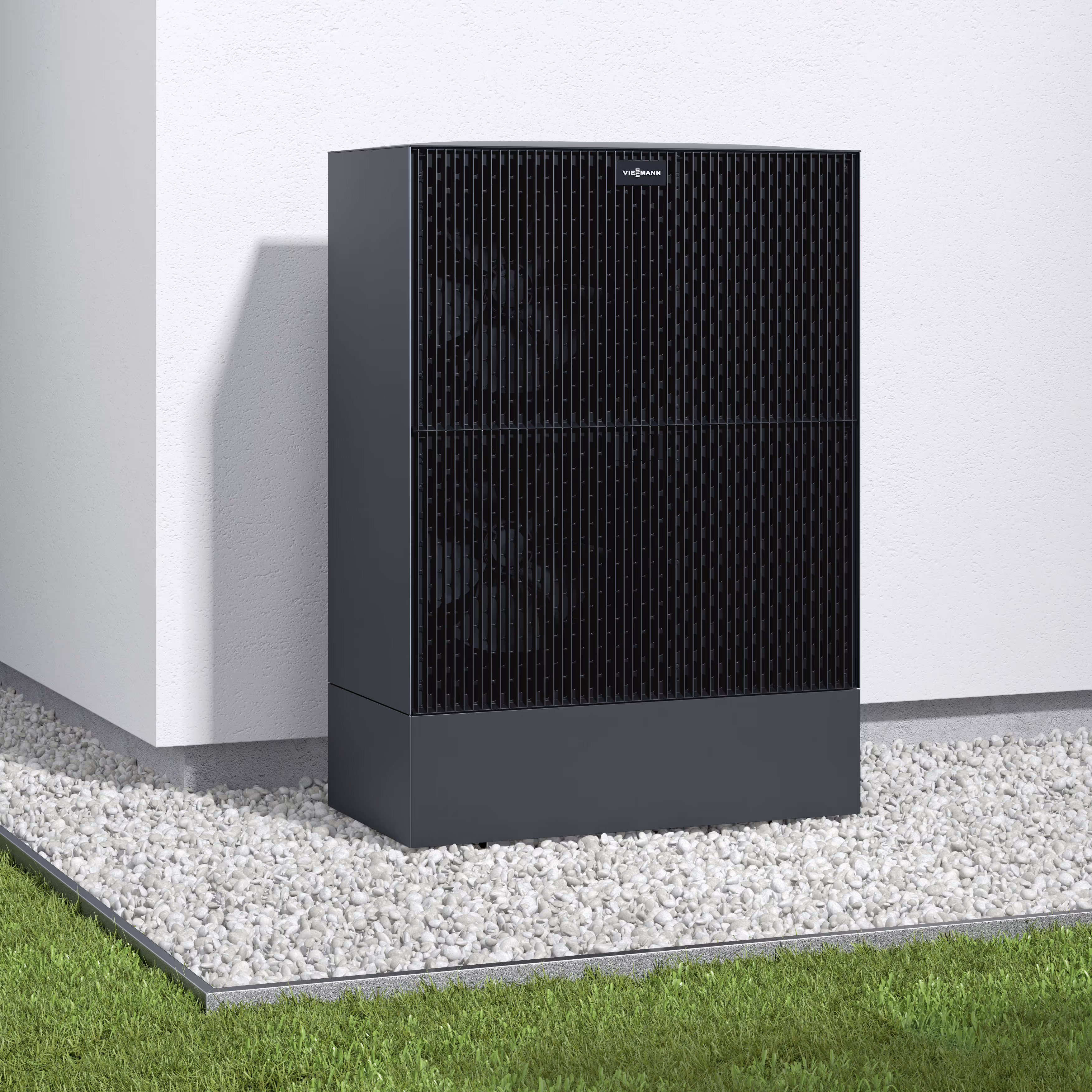 Eine schwarze Außeneinheit einer Viessmann Wärmepumpe steht auf weißen Kieseln neben einer Hauswand.