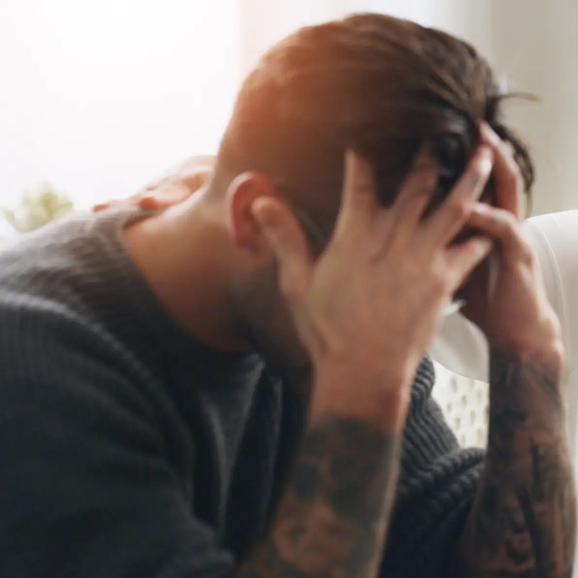 A distressed man sitting with his head in his hands.