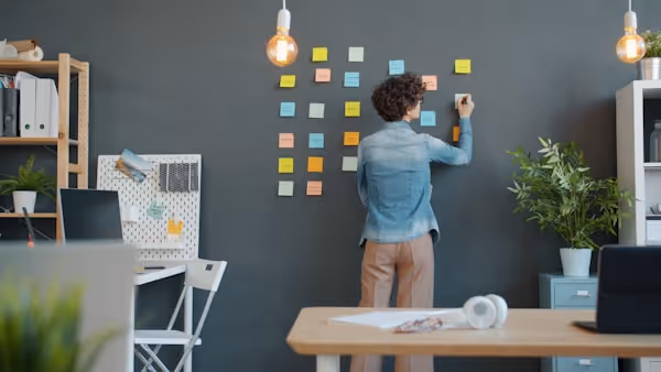 young businesswoman writing on paper sticky notes on wall working alone concentrated on creative job. People and corporate activities concept.