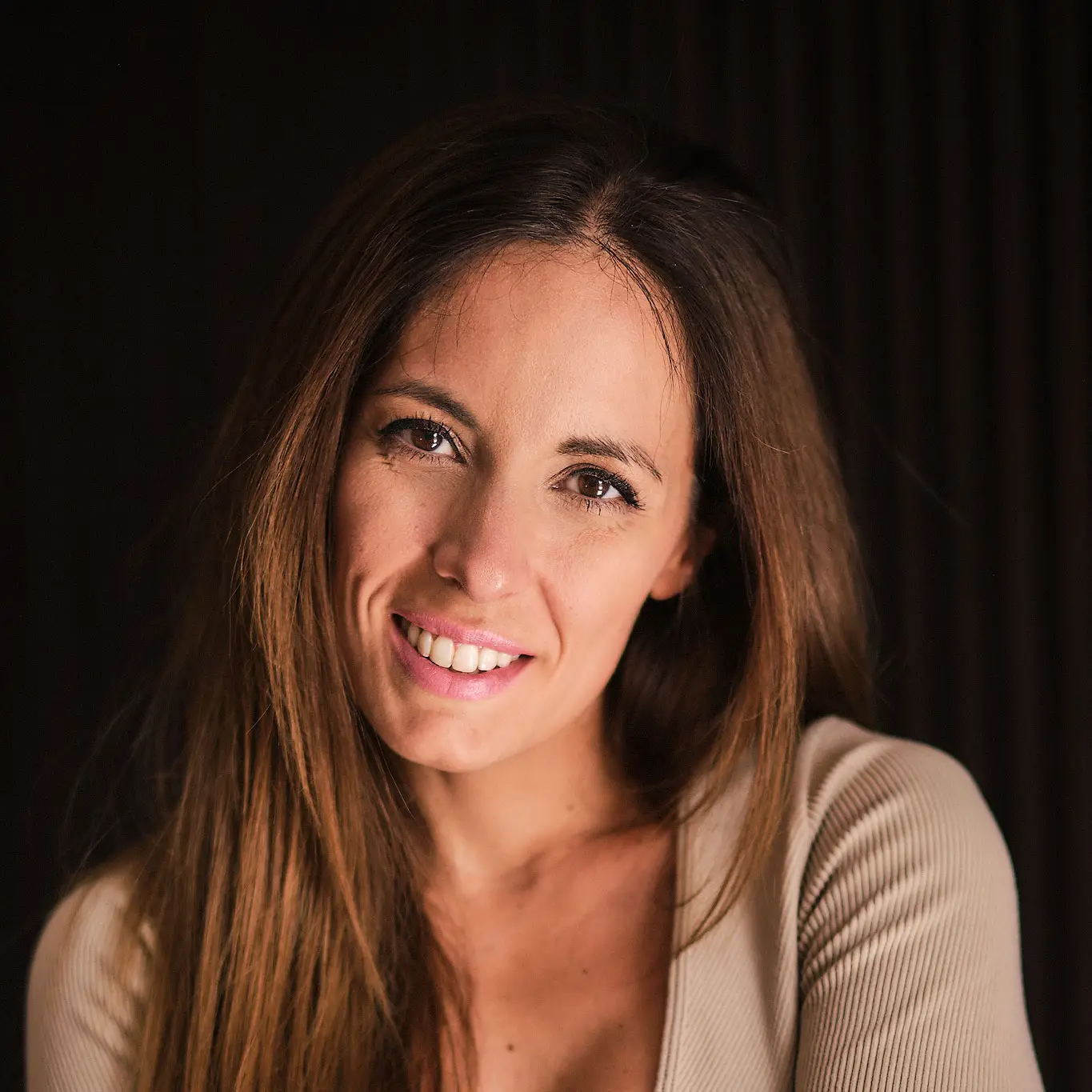 Retrato de Laura sonriendo, de frente y sobre fondo oscuro