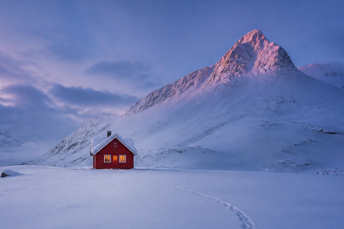 La misma cabaña roja desplazada a un punto fuerte inferior izquierdo, con la montaña completa a la derecha y el rastro de huellas en la nieve conduciendo hasta ella