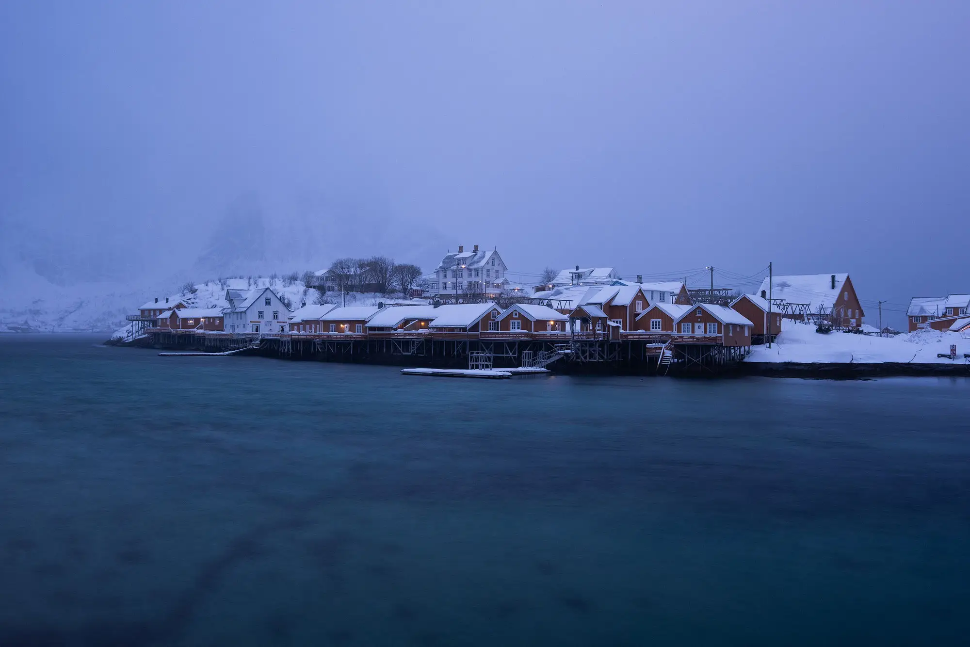El mismo puerto pesquero nevado fotografiado con una exposición de ocho segundos, con la superficie del mar convertida en una lámina lisa