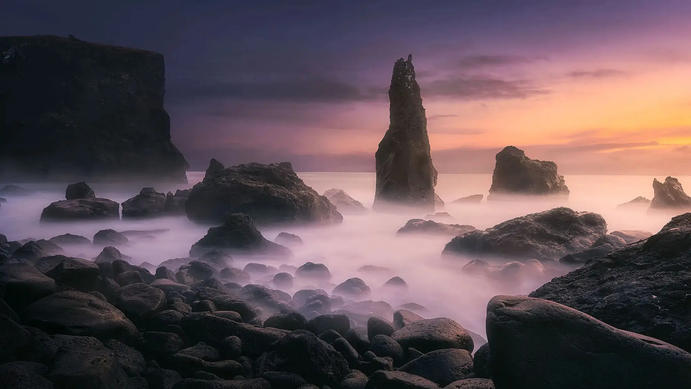Costa fotografiada con una exposición larga, con el agua convertida en bruma y las nubes arrastradas en el cielo