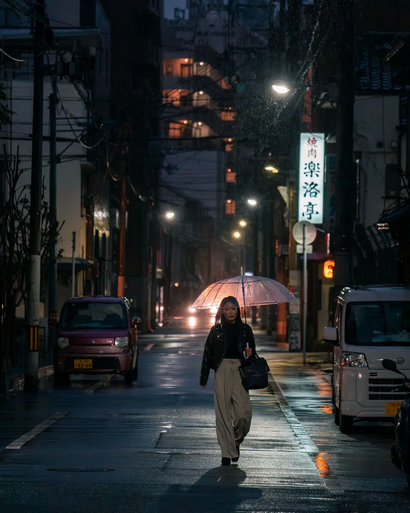 La misma calle japonesa de noche fotografiada a 1/250 de segundo: la persona que camina con el paraguas sale definida
