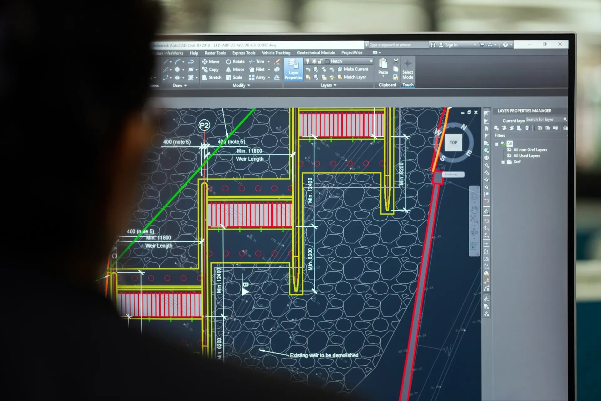 Person blickt auf einen Monitor mit einer technischen CAD-Konstruktionszeichnung.