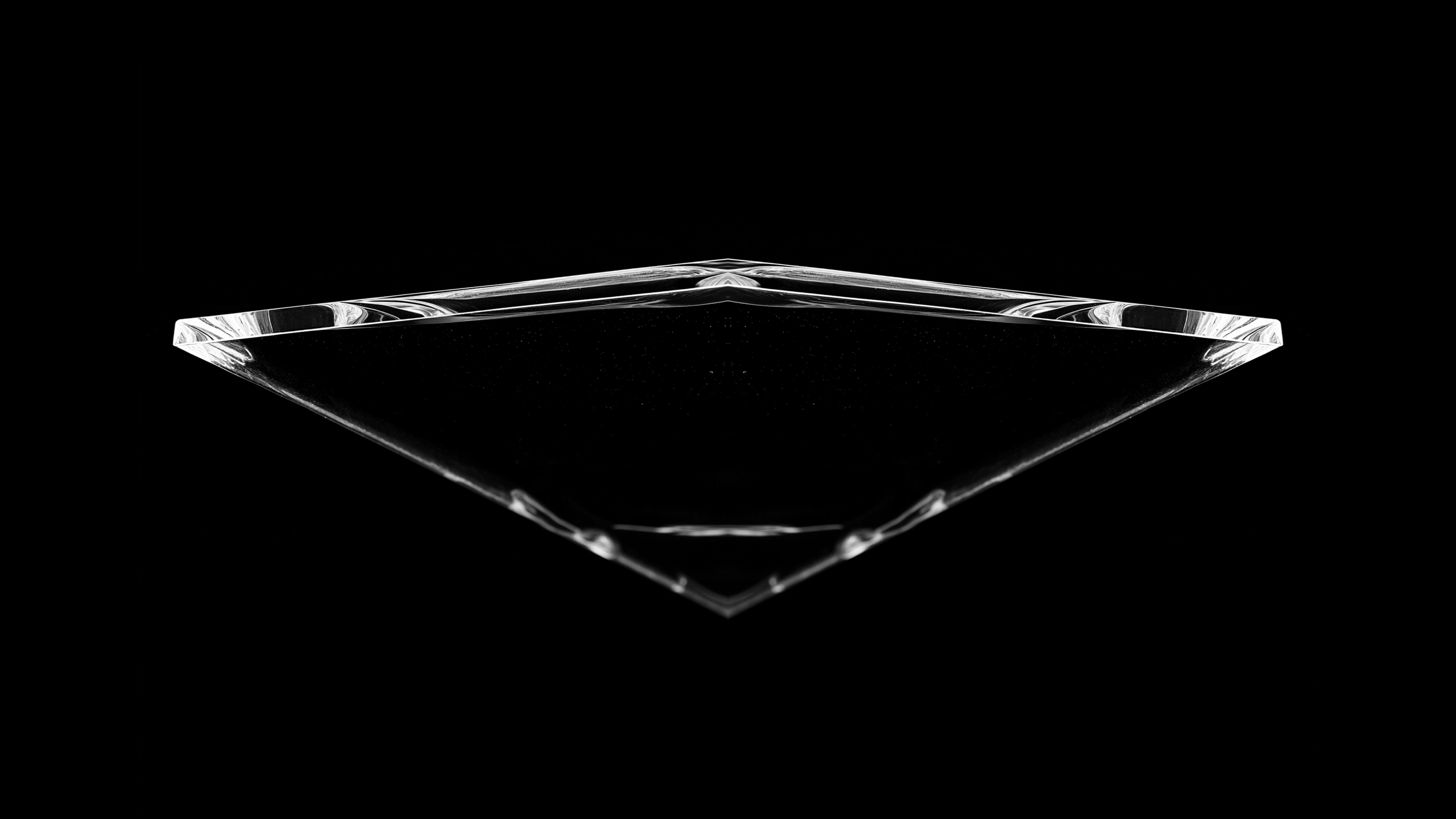 Schwarzhintergrund mit einem transparenten, dreiecksförmigen Kristallobjekt, das von unten nach oben zeigt.