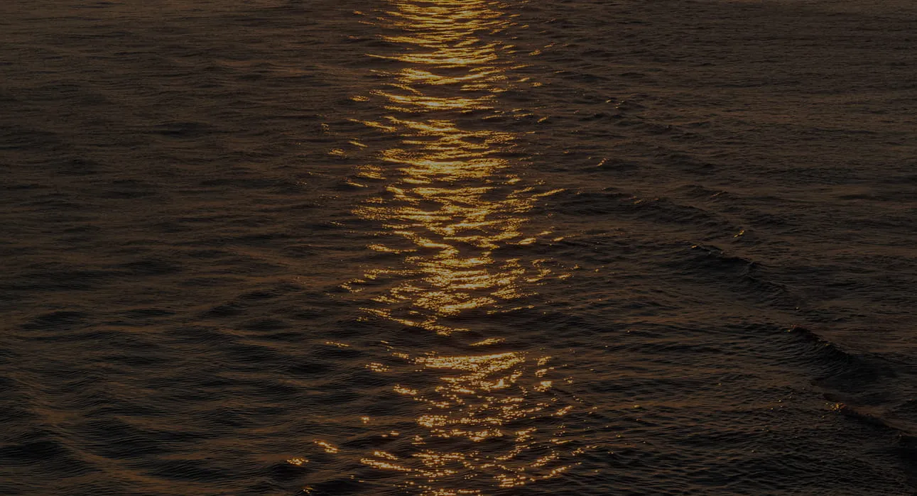 Golden sunlight reflecting and shimmering on dark ocean waves at dusk or dawn.