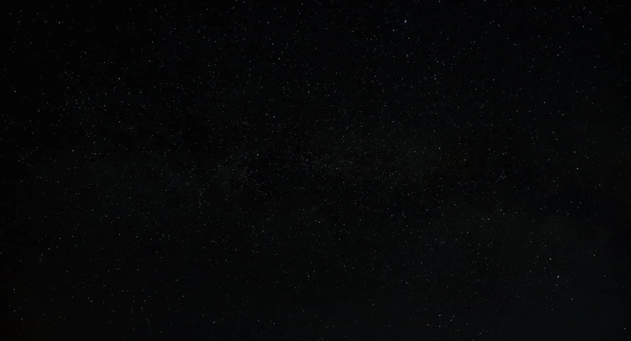 Clear night sky filled with numerous stars and faint hints of the Milky Way galaxy.