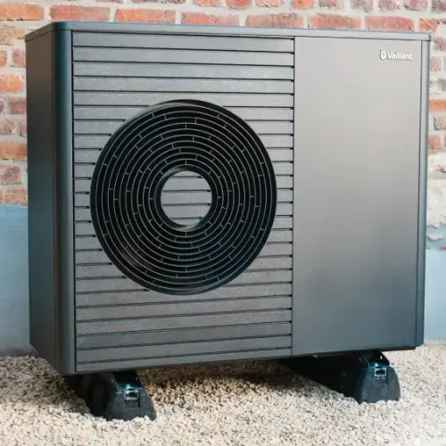 Moderne Vaillant Wärmepumpe an einer Ziegelmauer montiert auf Kiesboden.