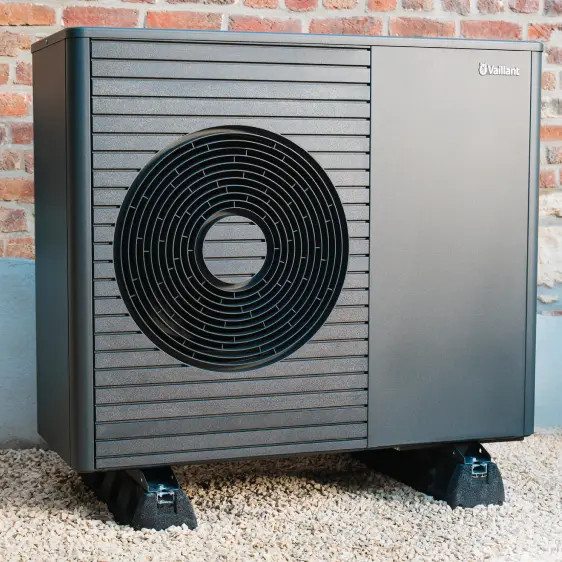 Moderne Vaillant Wärmepumpe an einer Ziegelmauer montiert auf Kiesboden.