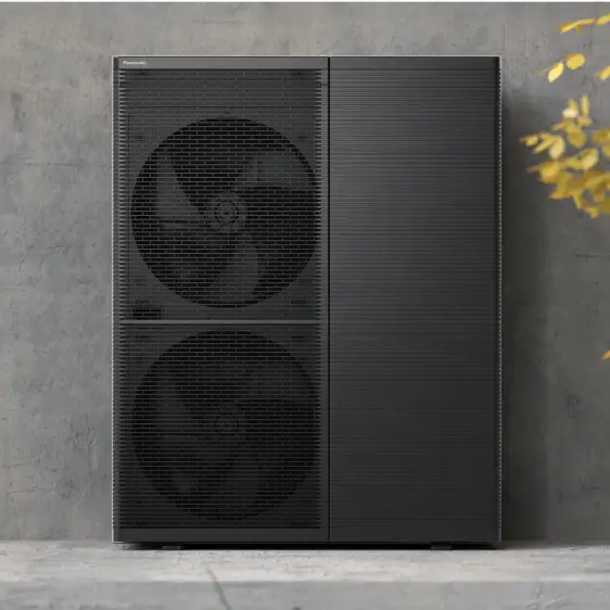 Große schwarze Panasonic Wärmepumpe mit zwei Lüftern an einer grauen Betonwand.