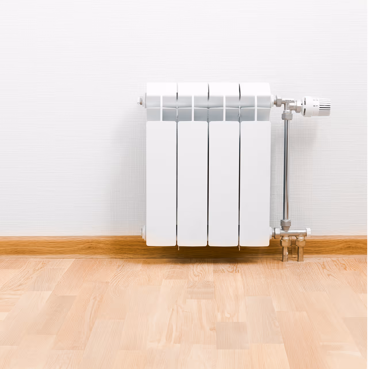 Weißer Heizkörper mit Thermostatventil an einer weißen Wand über einem Holzboden.