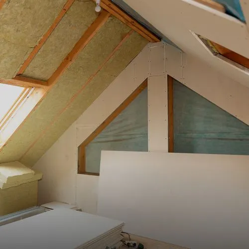 Dachbodendämmung in Arbeit mit Glaswolle und Gipsplatten, Dachfenster links.