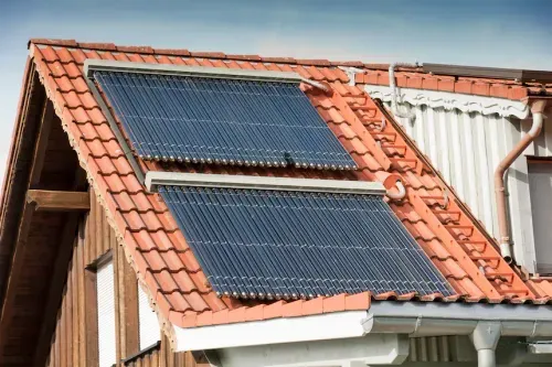 Hausdach mit roten Ziegeln und zwei installierten Solarthermie-Kollektoren zur umweltfreundlichen Energiegewinnung.