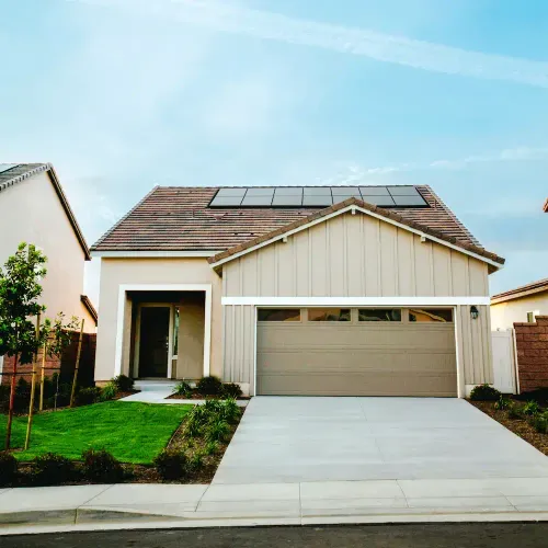 Modernes Einfamilienhaus mit Garage, solarbetriebenen Solarpaneelen auf dem Dach und gepflegtem Vorgarten.