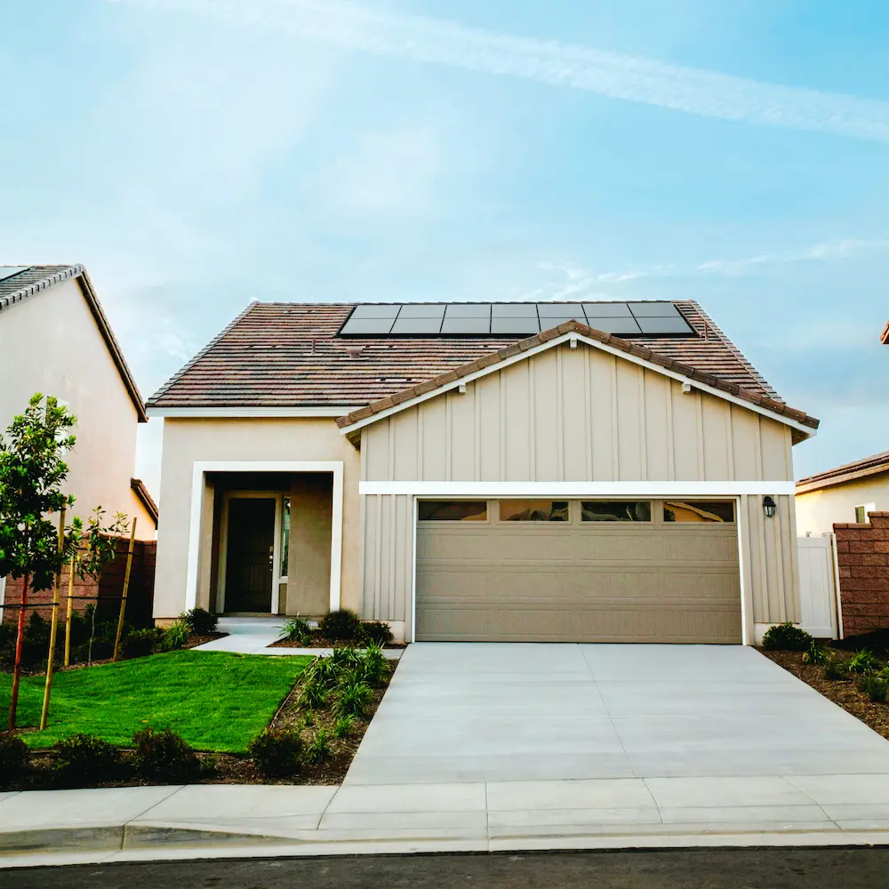Modernes Einfamilienhaus mit Garage, solarbetriebenen Solarpaneelen auf dem Dach und gepflegtem Vorgarten.