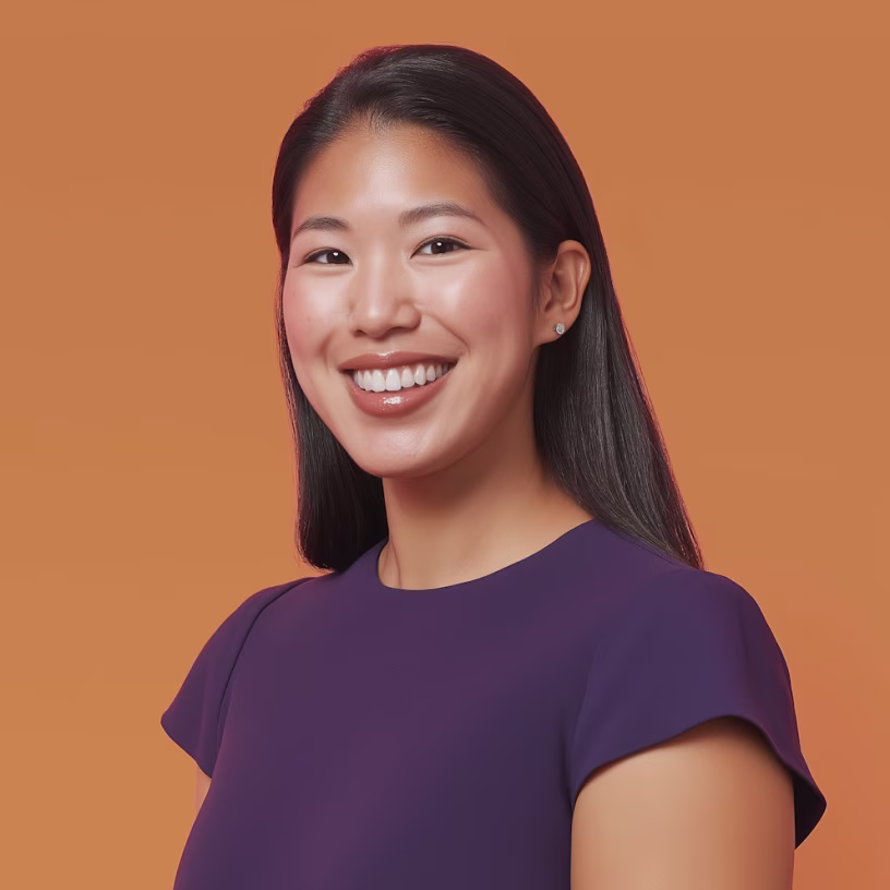 Smiling Asian woman with long black hair wearing a purple top against a warm brown background.