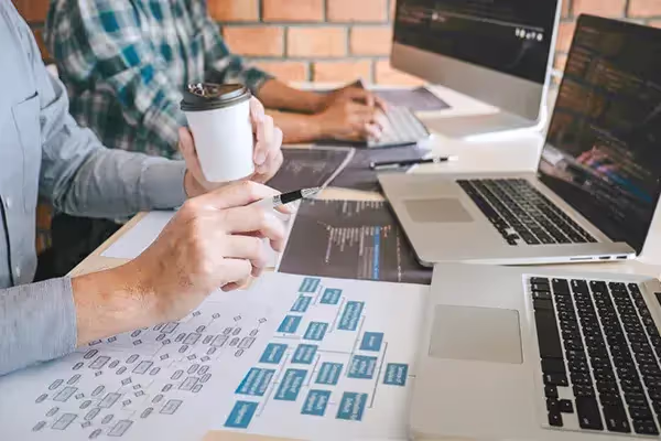 Deux personnes en discussion face à un ordinateur pour créer un site internet gratuitement.