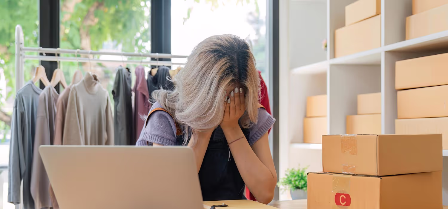 Commerçante en ligne stressée devant son ordinateur à cause d’un manque de ventes sur sa boutique e-commerce.