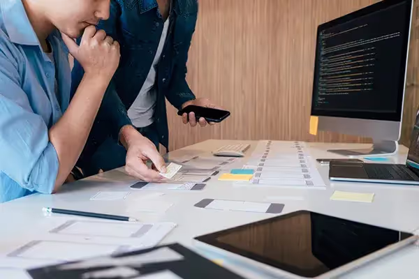 Deux collègues faisant partie de la même agence web et discutant ensemble d'un projet.