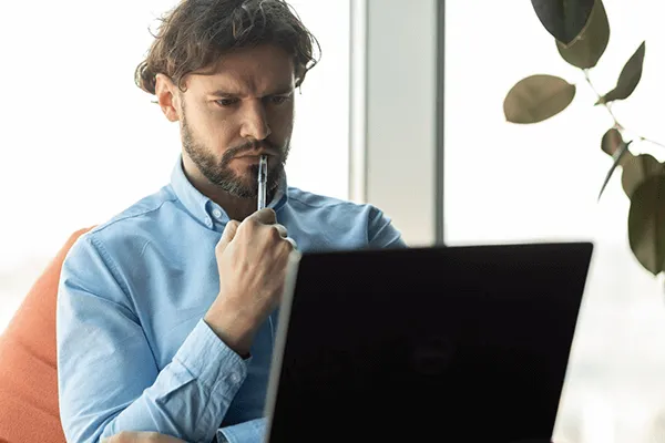 Un client face à son pc qui est occupé à réfléchir pour son site internet : le faire soi-même ou le confier à une agence web.