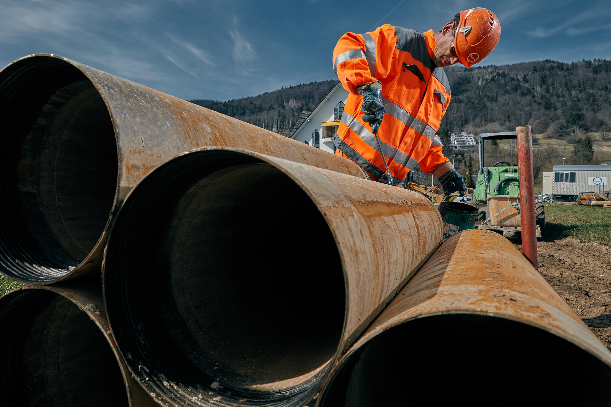 Mitarbeiter bearbeitet Stahlrohre für den Rohrleitungsbau auf einer Baustelle.