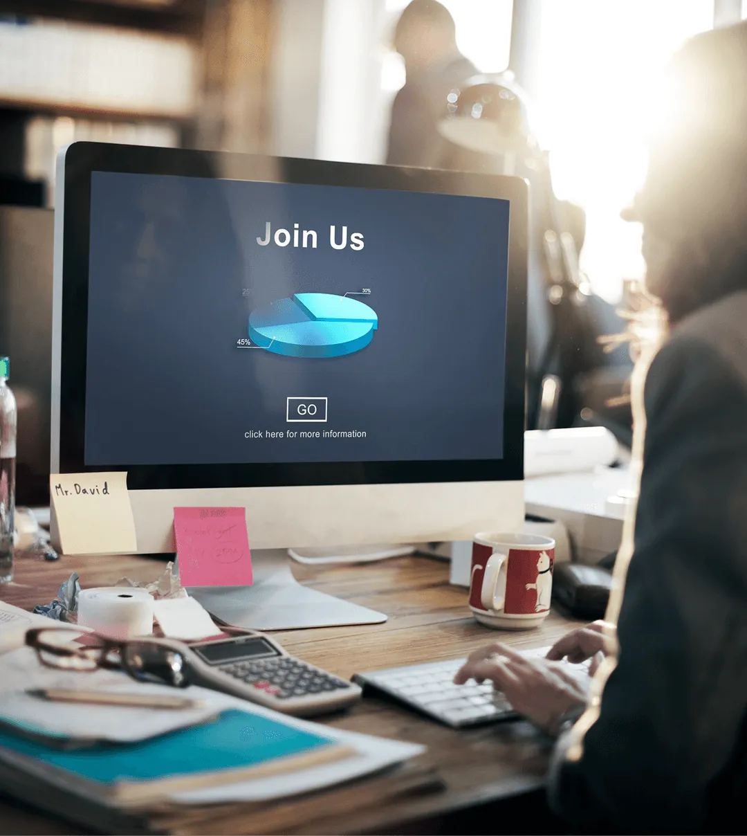 Computer monitor on a busy desk showing a dark “Join Us” signup screen.