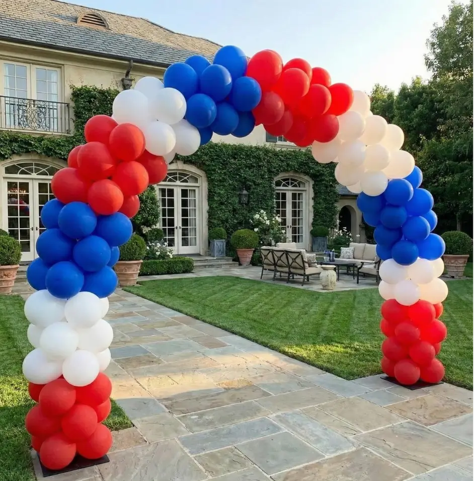 Red, white, and blue balloon arch set up on a stone patio in front of a house with green ivy on the walls in Dallas.