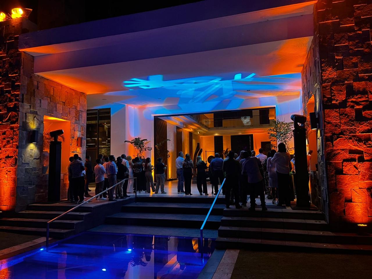 Iluminación arquitectónica en ámbar y azul con proyección de gobo sobre la fachada de un venue durante un evento nocturno