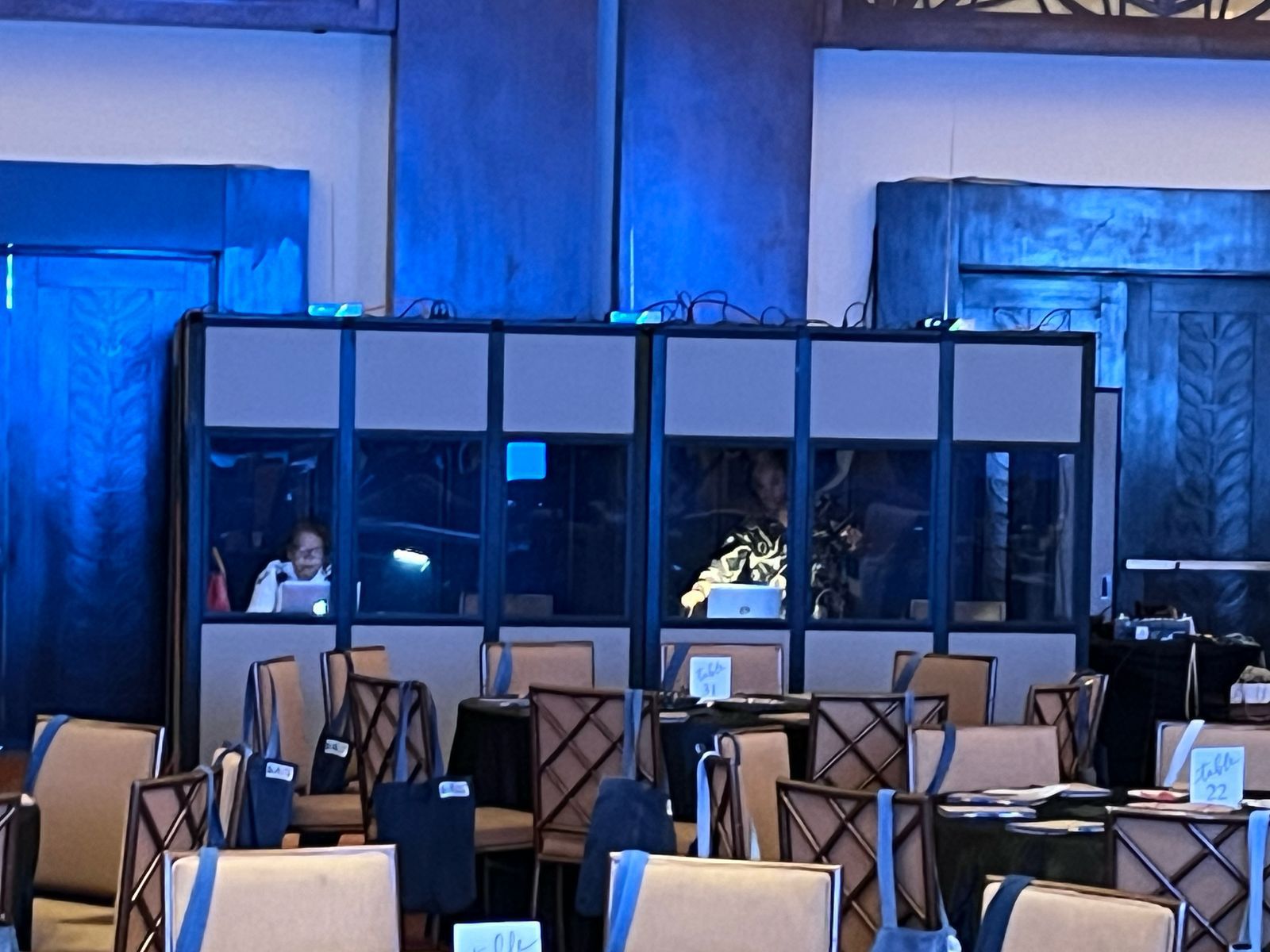 Cabinas de interpretación simultánea con intérpretes trabajando al fondo de un salón de congreso