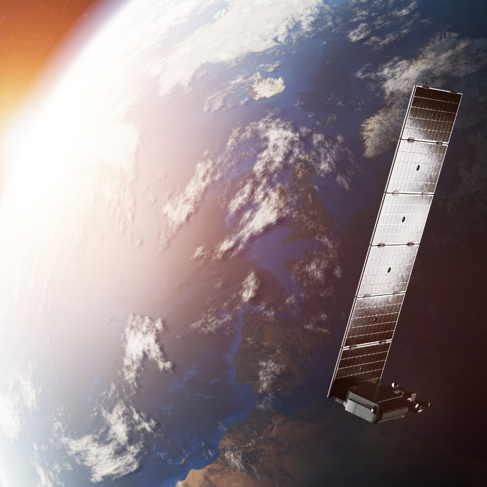 Smiling woman with long dark hair wearing a navy blazer and white blouse, seated with hands resting on her knee against a dark background.
