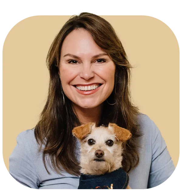 Pet Behaviourist and Nutritionist Lara Shannon smiles while holding a small dog with a bandana.