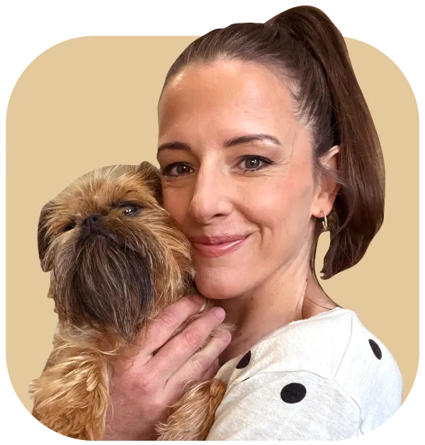 Integrative Veterinarian Dr Nicole Rous smiles while hugging a dog.