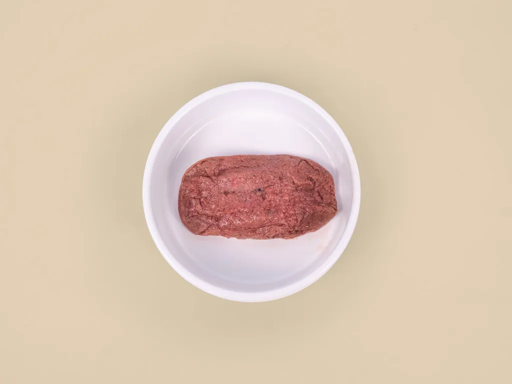 A patty of Combo Raw Cat Food in a bowl.