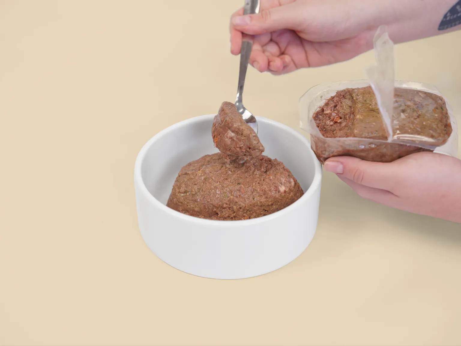 Hands spooning a patty of Big Dog Pet Foods Wellbeing Raw Diet into a bowl.